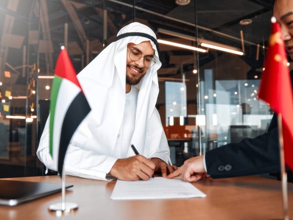 Flags of the China and UAE on the table during negotiations between diplomats and businessmen. Representatives sit opposite each other and discuss relations between countries, signing a treaty.